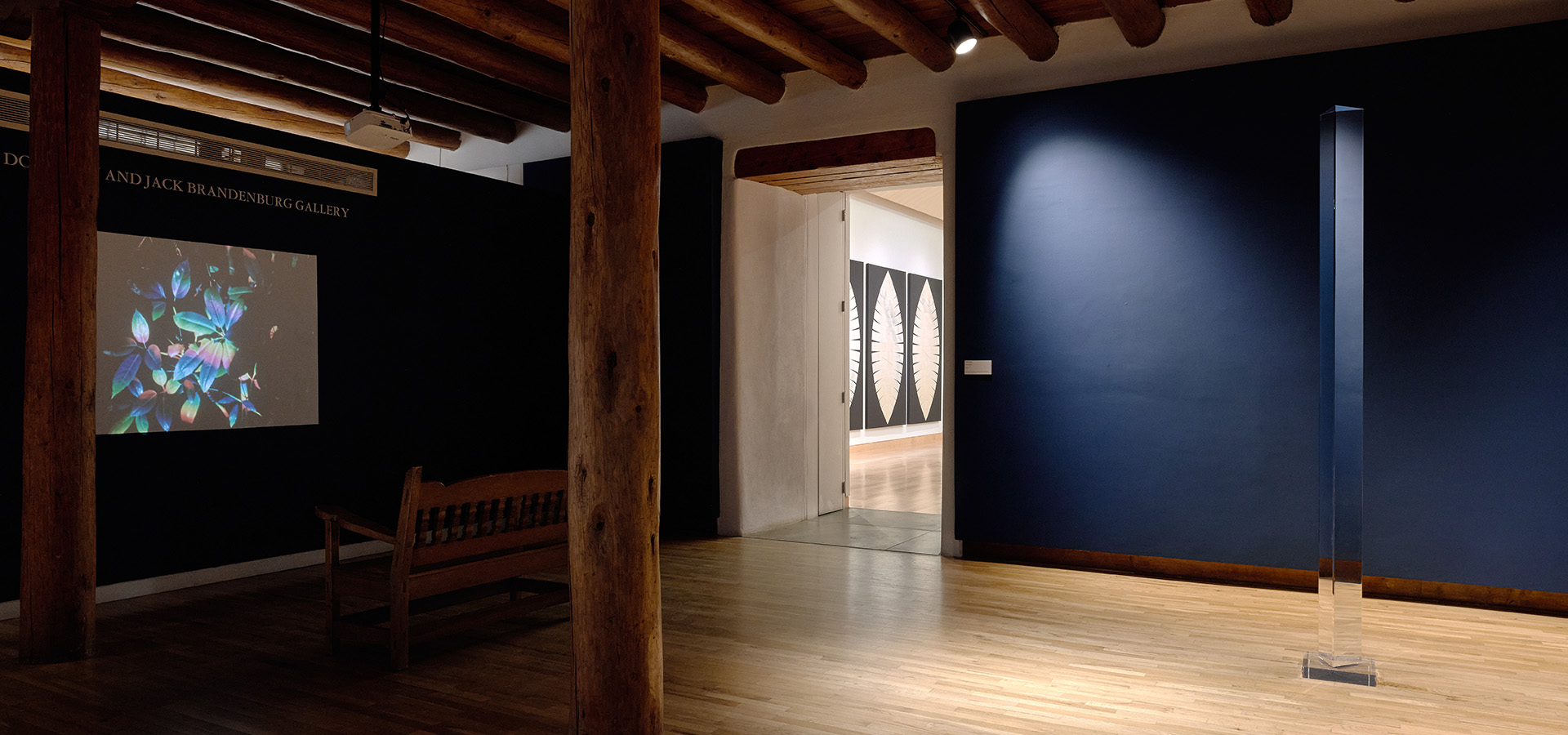 A digital display and a tall prism in a dark blue gallery at Harwood Museum.