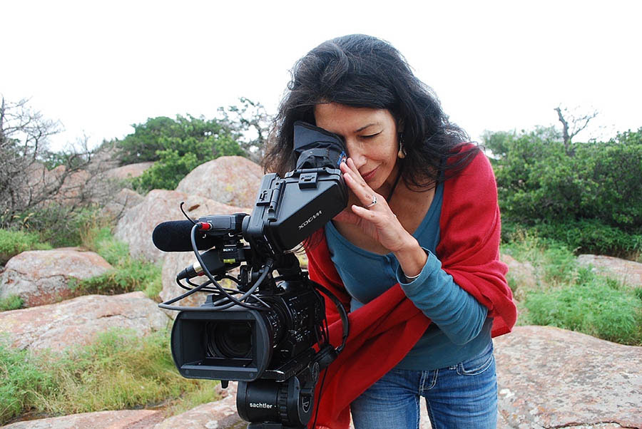 Jill Momaday leans over to look into viewfinder of a film camera on location in nature