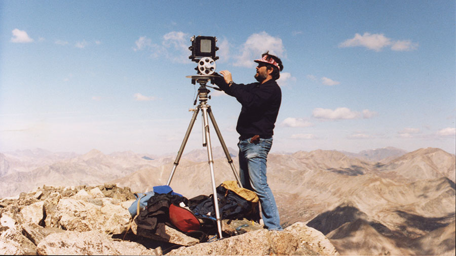 Gus Foster atop Mt Yale with a film camera and tripod
